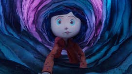A still from Coraline, showing the titular character wearing pyjamas crawling through a mysterious, slightly glowing, circular cave.
