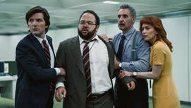The main cast of Severance, including Adam Scott, Zack Cherry, John Turturro, and Britt Lower, hudled together in an office space looking at something offscreen.